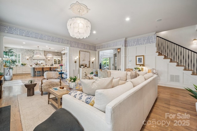 3519 Mcpherson St, Waxhaw, NC 28173 - living room featuring light wood-style floors, crown molding, stairs, a decorative wall, and wallpapered walls