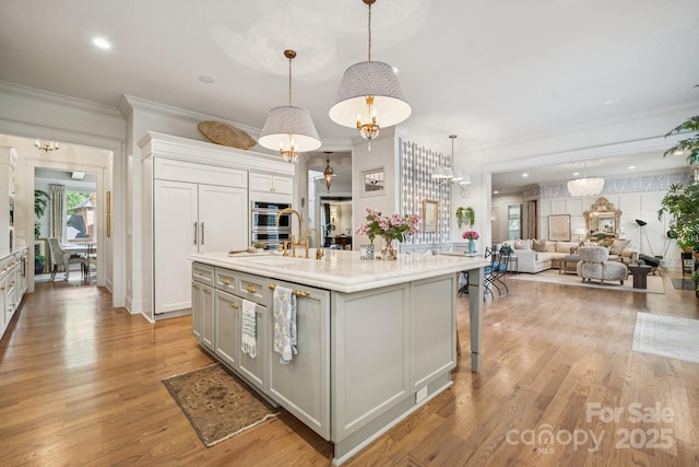 3519 Mcpherson St, Waxhaw, NC 28173 - kitchen with an island with sink, ornamental molding, open floor plan, light countertops, and light wood-style floors