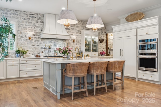 3519 Mcpherson St, Waxhaw, NC 28173 - kitchen with light countertops, custom exhaust hood, white cabinets, light wood-style floors, and wallpapered walls
