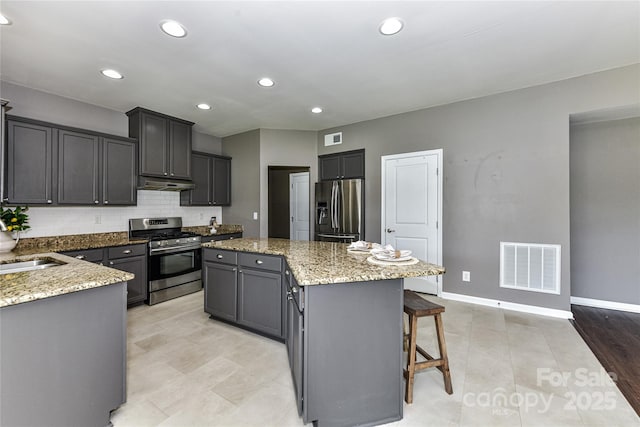 3533 Catherine Creek Pl, Davidson, NC 28036 - kitchen featuring stainless steel appliances, a center island, under cabinet range hood, light stone counters, and a breakfast bar