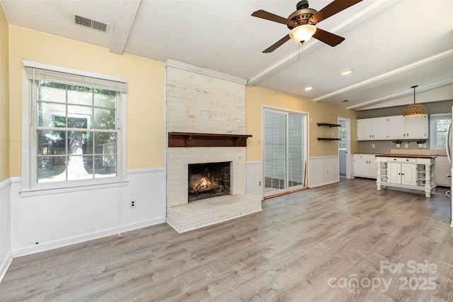 7017 Brookgreen Ter, Matthews, NC 28104 - unfurnished living room featuring wainscoting, a ceiling fan, light wood-style flooring, and a fireplace