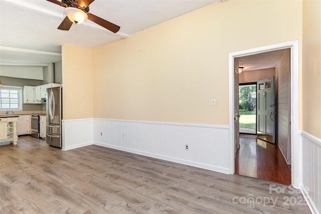 7017 Brookgreen Ter, Matthews, NC 28104 - unfurnished living room with wood finished floors, a ceiling fan, and a wainscoted wall