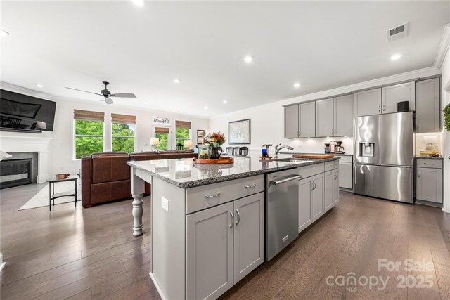 1240 Pebble Grove Dr, Clover, SC 29710 - kitchen with appliances with stainless steel finishes, gray cabinets, open floor plan, an island with sink, and ornamental molding