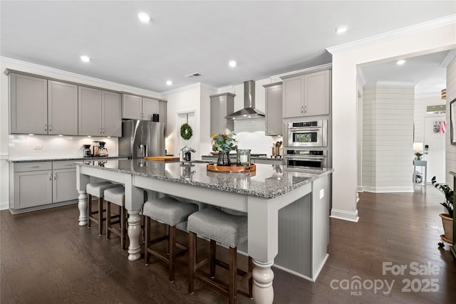 1240 Pebble Grove Dr, Clover, SC 29710 - kitchen with wall chimney range hood, gray cabinetry, appliances with stainless steel finishes, a breakfast bar, and a center island with sink