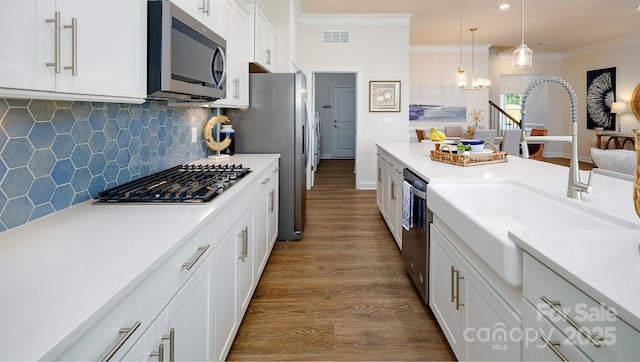 4129 Duplin Dr, Charlotte, NC 28214 - kitchen featuring appliances with stainless steel finishes, ornamental molding, dark wood-style floors, white cabinetry, and light countertops