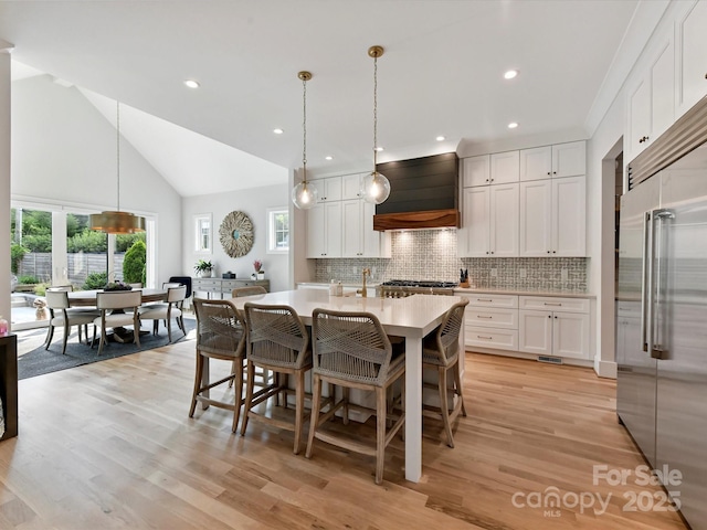 615 Melbourne Ct, Charlotte, NC 28209 - kitchen with custom range hood, stainless steel built in refrigerator, light countertops, decorative backsplash, and a breakfast bar