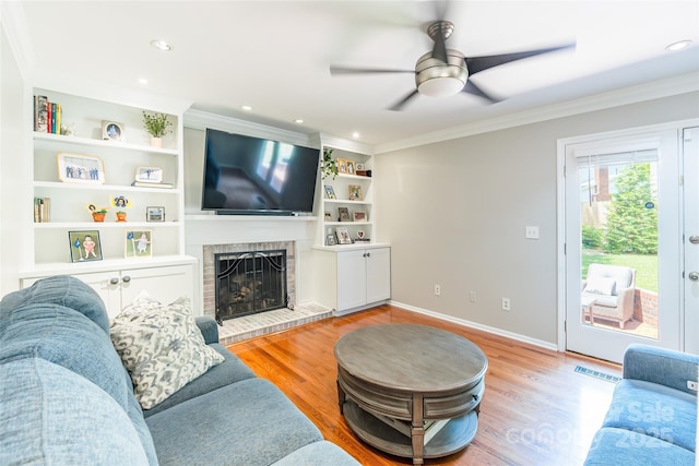 1220 Merribrook Dr, Matthews, NC 28105 - living area featuring a ceiling fan, ornamental molding, a brick fireplace, light wood-style flooring, and built in shelves