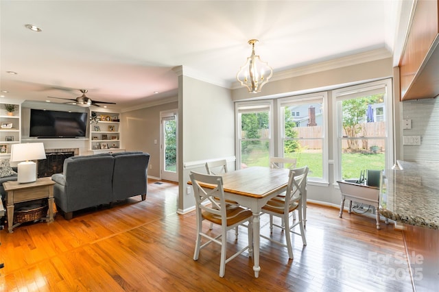 1220 Merribrook Dr, Matthews, NC 28105 - dining area featuring crown molding, a chandelier, light wood-style flooring, a ceiling fan, and a fireplace