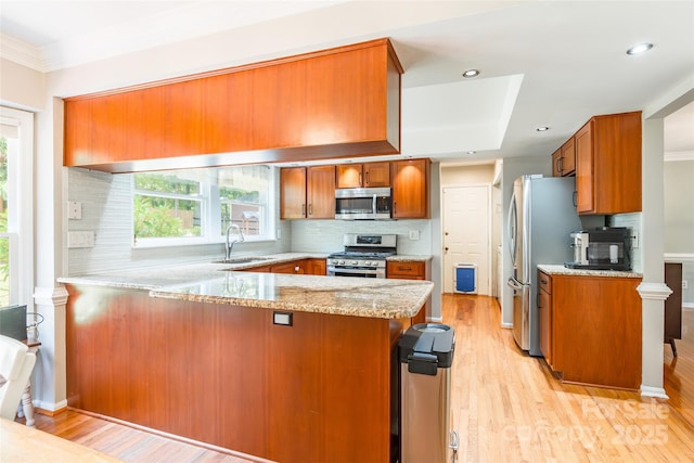 1220 Merribrook Dr, Matthews, NC 28105 - kitchen featuring appliances with stainless steel finishes, a peninsula, brown cabinets, light wood-style flooring, and recessed lighting