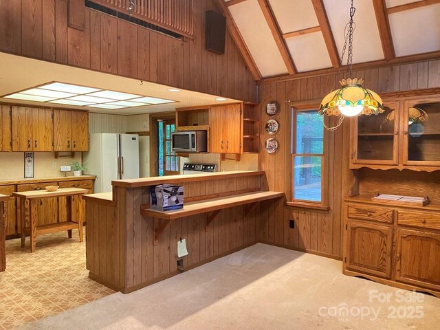 268 Poor Boy Ln, Whittier, NC 28789 - kitchen featuring stainless steel microwave, freestanding refrigerator, open shelves, wood walls, and brown cabinetry