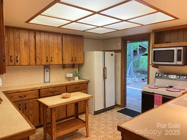 268 Poor Boy Ln, Whittier, NC 28789 - kitchen featuring stainless steel microwave, range with electric cooktop, light countertops, brown cabinets, and freestanding refrigerator