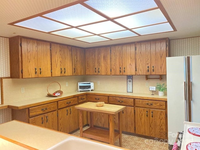 268 Poor Boy Ln, Whittier, NC 28789 - kitchen featuring freestanding refrigerator, light countertops, brown cabinets, and wallpapered walls