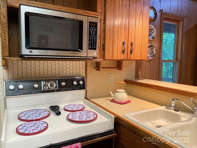 268 Poor Boy Ln, Whittier, NC 28789 - kitchen with white electric range oven, stainless steel microwave, light countertops, brown cabinetry, and wallpapered walls