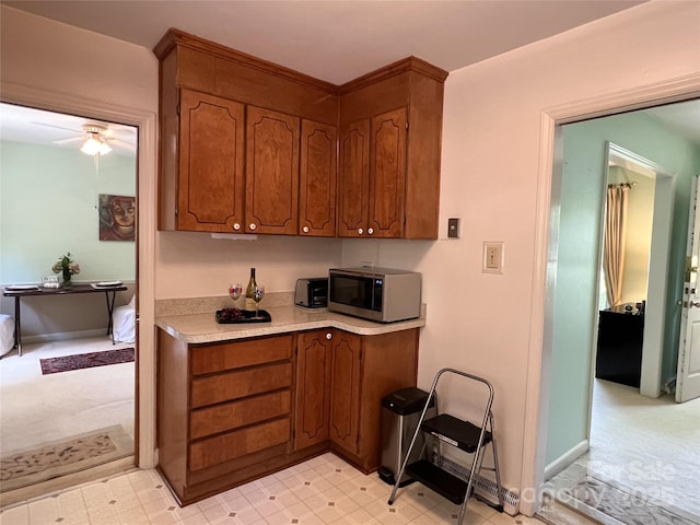 5938 Sharon Rd, Charlotte, NC 28210 - kitchen with stainless steel microwave, light countertops, brown cabinets, and a ceiling fan