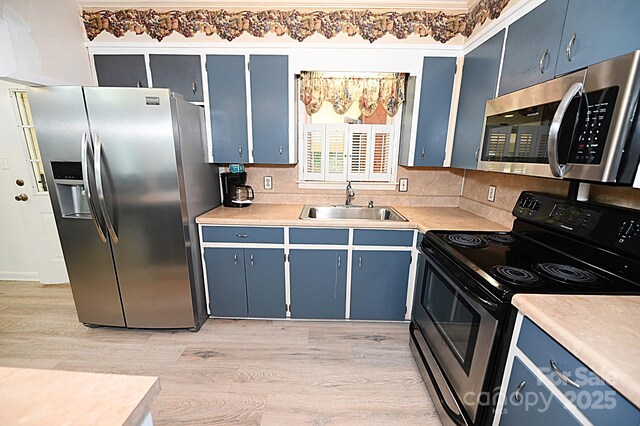 112 Lovelady Rd, Valdese, NC 28690 - kitchen with appliances with stainless steel finishes, blue cabinets, light wood-type flooring, and decorative backsplash