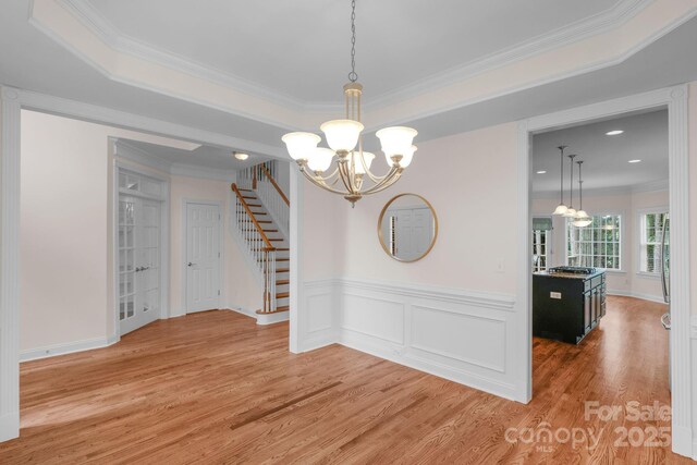 8606 Gresham Dr, Waxhaw, NC 28173 - unfurnished dining area featuring a chandelier, ornamental molding, light wood-style floors, stairway, and wainscoting