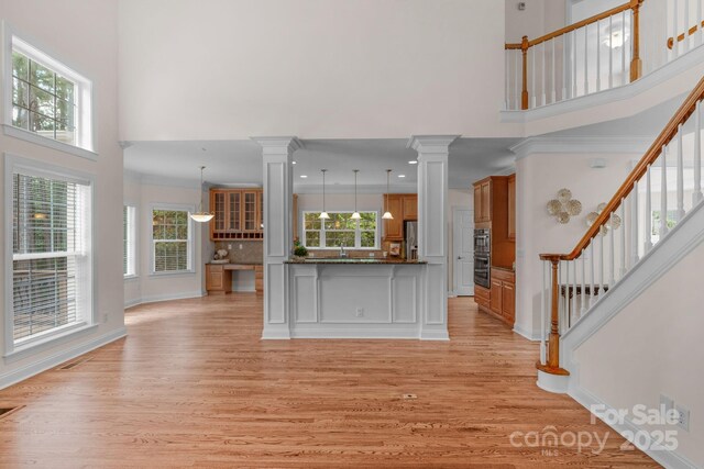8606 Gresham Dr, Waxhaw, NC 28173 - unfurnished living room with a towering ceiling, ornate columns, light wood-type flooring, and plenty of natural light