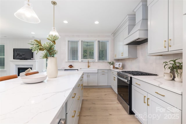 4114 Mantle Ct, Charlotte, NC 28205 - kitchen featuring custom range hood, stainless steel range with gas stovetop, decorative backsplash, light wood-style flooring, and light stone counters
