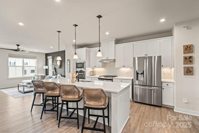 932 Portrush Ln, Tega Cay, SC 29708 - kitchen featuring appliances with stainless steel finishes, under cabinet range hood, a kitchen bar, light countertops, and recessed lighting