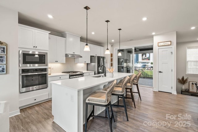 932 Portrush Ln, Tega Cay, SC 29708 - kitchen with stainless steel appliances, recessed lighting, a center island with sink, light countertops, and wood finished floors