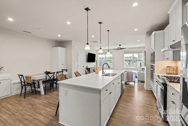 932 Portrush Ln, Tega Cay, SC 29708 - kitchen with appliances with stainless steel finishes, a kitchen island with sink, light countertops, wood finished floors, and recessed lighting
