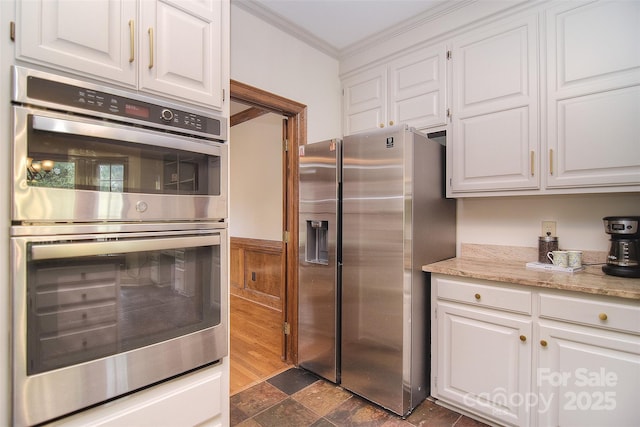 1482 Willow Oaks Trl, Matthews, NC 28104 - kitchen featuring appliances with stainless steel finishes, ornamental molding, white cabinets, dark stone finish floors, and light stone countertops