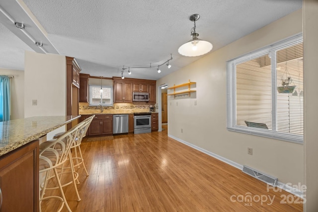 840 Deer Lake Run, Salisbury, NC 28146 - kitchen with stainless steel appliances, backsplash, light wood-style floors, a textured ceiling, and hanging light fixtures