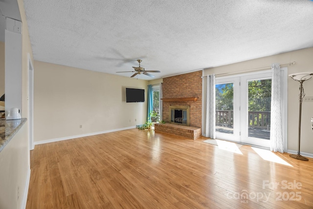 840 Deer Lake Run, Salisbury, NC 28146 - unfurnished living room featuring a textured ceiling, light wood finished floors, a ceiling fan, and a brick fireplace