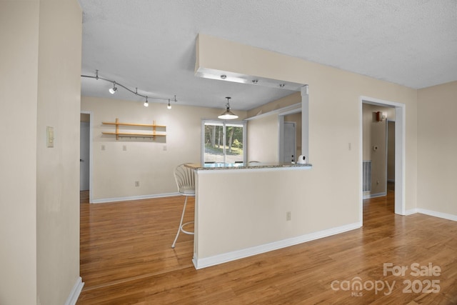 840 Deer Lake Run, Salisbury, NC 28146 - kitchen with wood finished floors, a textured ceiling, a breakfast bar area, and decorative light fixtures