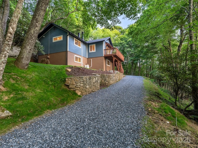 1065 Oak Ridge Ln, Mars Hill, NC 28754 - view of front of house with a wooden deck, stairway, gravel driveway, and stucco siding