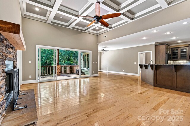 3450 4th Street Blvd NW, Hickory, NC 28601 - unfurnished living room with ceiling fan, a towering ceiling, a fireplace, beamed ceiling, and light wood-style flooring