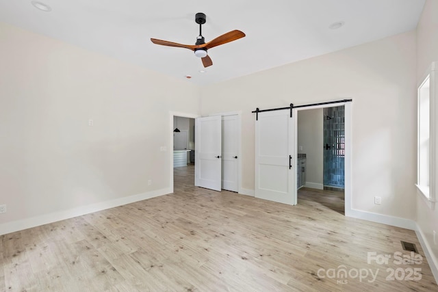 939 Rocky Mountain Rd, Lake Toxaway, NC 28747 - unfurnished bedroom with a barn door, wood finished floors, ceiling fan, and ensuite bathroom