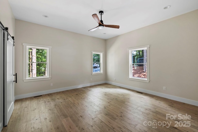 939 Rocky Mountain Rd, Lake Toxaway, NC 28747 - spare room with a barn door, plenty of natural light, ceiling fan, and light wood-style flooring