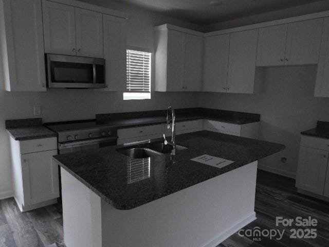 248 Mills Ave, Troutman, NC 28166 - kitchen featuring stainless steel microwave, dark wood-style flooring, electric stove, a center island with sink, and white cabinetry