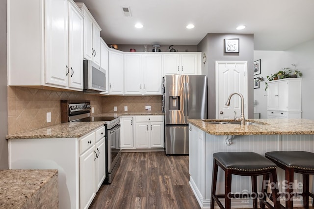 217 Fielding St, Mount Holly, NC 28120 - kitchen featuring appliances with stainless steel finishes, dark wood-style flooring, a kitchen breakfast bar, white cabinetry, and recessed lighting