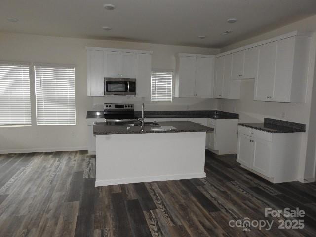 252 Mills Ave, Troutman, NC 28166 - kitchen featuring stainless steel appliances, dark countertops, an island with sink, white cabinetry, and dark wood finished floors