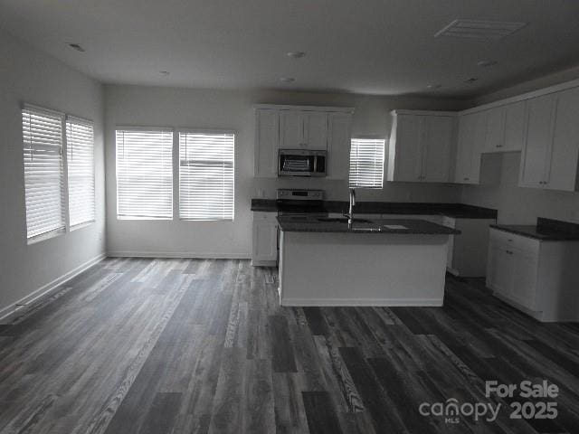 260 Mills Ave, Troutman, NC 28166 - kitchen featuring appliances with stainless steel finishes, dark wood-type flooring, an island with sink, and dark countertops