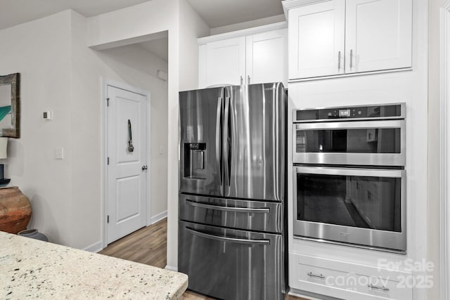 9021 Myrna Dr, Gastonia, NC 28056 - kitchen featuring appliances with stainless steel finishes, white cabinets, light wood-type flooring, and light stone countertops