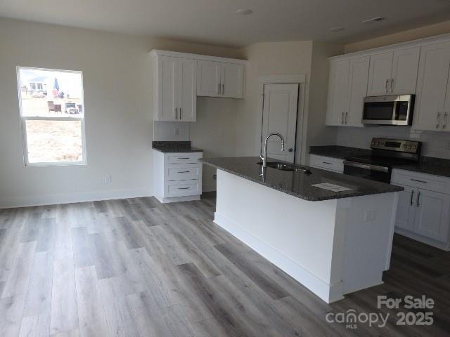 212 Sugar Hill Rd, Troutman, NC 28166 - kitchen featuring appliances with stainless steel finishes, dark countertops, and a center island with sink