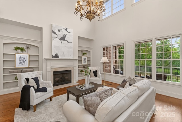1505 Hawkstone Dr, Waxhaw, NC 28173 - living area with built in shelves, a high ceiling, a chandelier, a premium fireplace, and wood finished floors