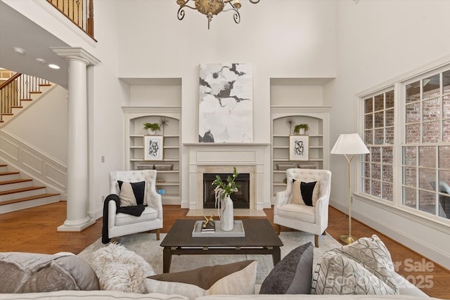 1505 Hawkstone Dr, Waxhaw, NC 28173 - living room featuring a towering ceiling, stairs, built in shelves, a glass covered fireplace, and wood finished floors