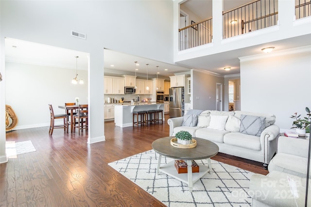 208 Canoe Pole Ln, Mooresville, NC 28117 - living area featuring a high ceiling, crown molding, dark wood-type flooring, and a chandelier