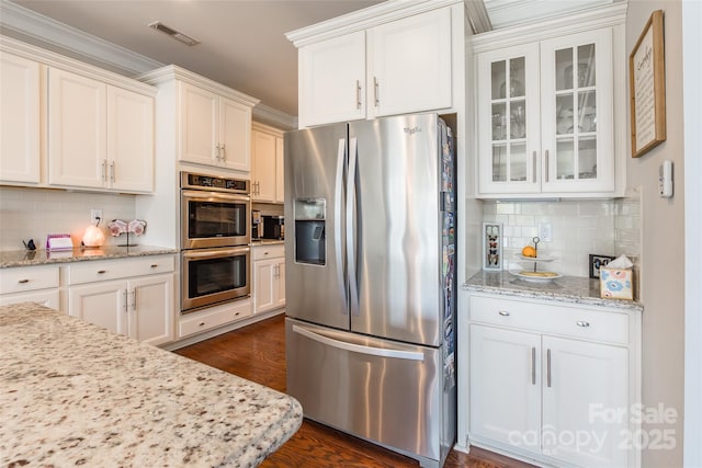 208 Canoe Pole Ln, Mooresville, NC 28117 - kitchen with stainless steel appliances, tasteful backsplash, glass insert cabinets, white cabinetry, and dark wood-style flooring