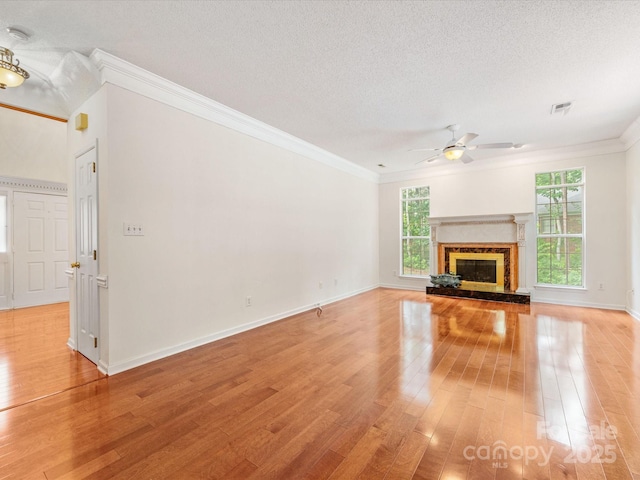 15139 Wiltshire Manor Dr, Charlotte, NC 28278 - unfurnished living room featuring crown molding, ceiling fan, light wood-style floors, a textured ceiling, and a glass covered fireplace