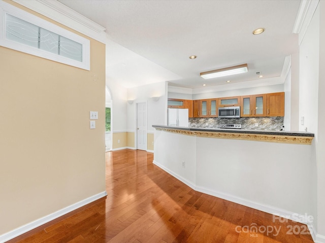 15139 Wiltshire Manor Dr, Charlotte, NC 28278 - kitchen with appliances with stainless steel finishes, brown cabinetry, wood finished floors, glass insert cabinets, and tasteful backsplash