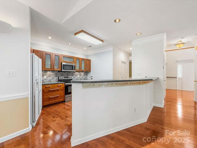 15139 Wiltshire Manor Dr, Charlotte, NC 28278 - kitchen with appliances with stainless steel finishes, brown cabinetry, wood finished floors, a peninsula, and decorative backsplash