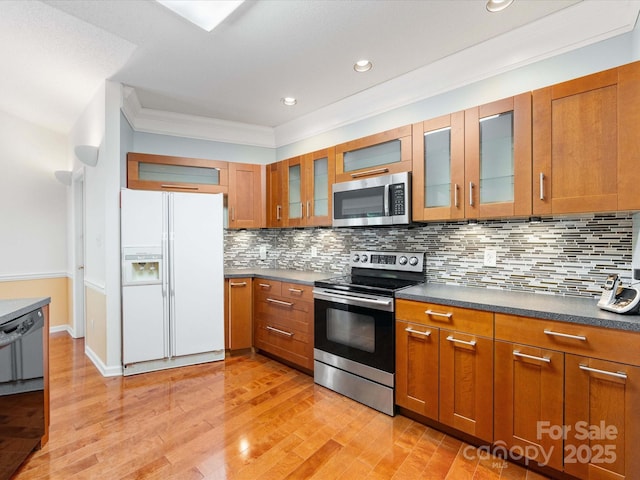 15139 Wiltshire Manor Dr, Charlotte, NC 28278 - kitchen with appliances with stainless steel finishes, brown cabinetry, dark countertops, tasteful backsplash, and crown molding
