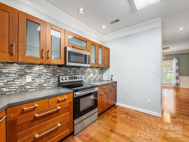 15139 Wiltshire Manor Dr, Charlotte, NC 28278 - kitchen with stainless steel appliances, ornamental molding, light wood-type flooring, dark countertops, and brown cabinetry