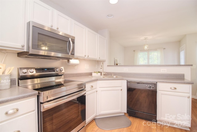 2620 Brackley Pl NW, Concord, NC 28027 - kitchen featuring appliances with stainless steel finishes, a peninsula, white cabinets, light wood-style flooring, and light countertops