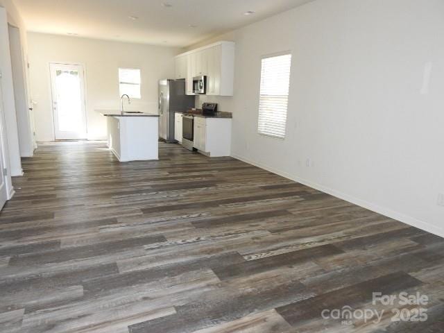 118 Carrisa Ln, Troutman, NC 28166 - kitchen featuring appliances with stainless steel finishes, dark countertops, white cabinetry, dark wood-style flooring, and open floor plan